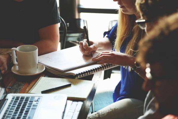 A female writing on a note pad in a meeting room.