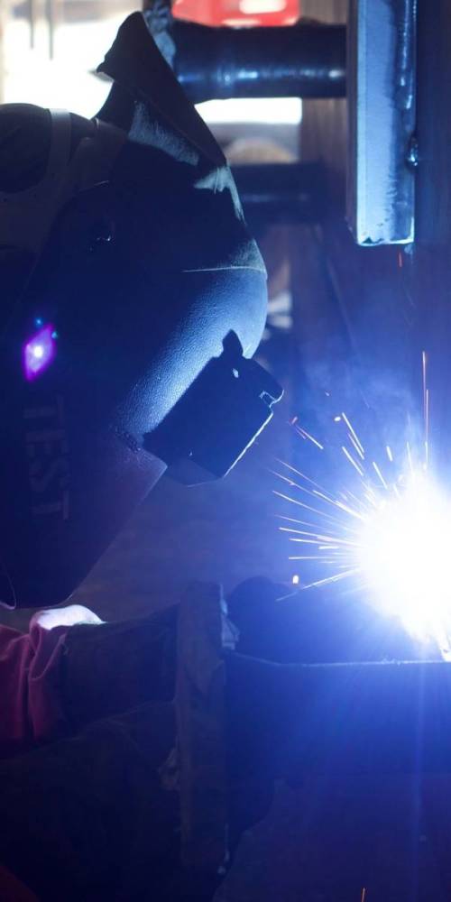 Picture of a welder in low light, welding.